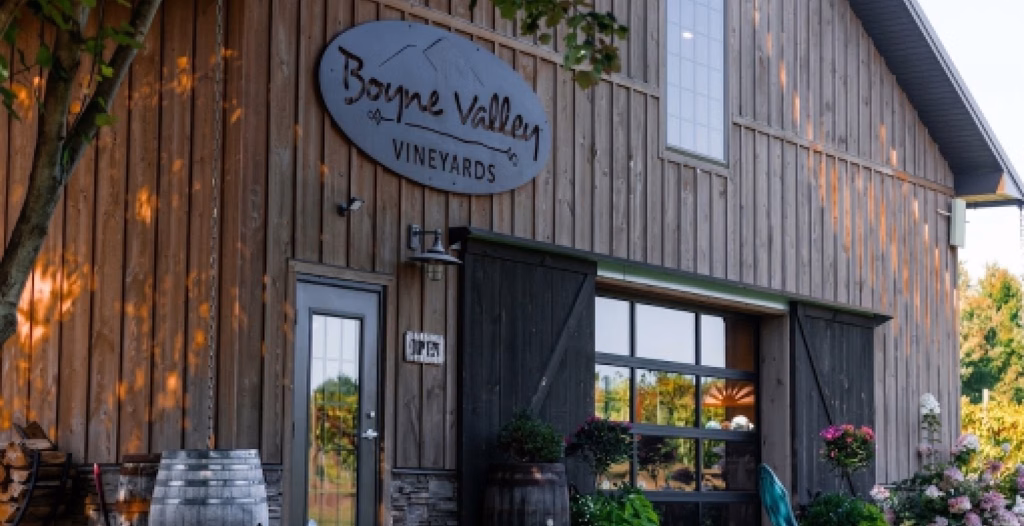 Exterior of Boyne Valley Vineyards barn featuring wooden siding, sliding doors, and a wine barrel out front.
